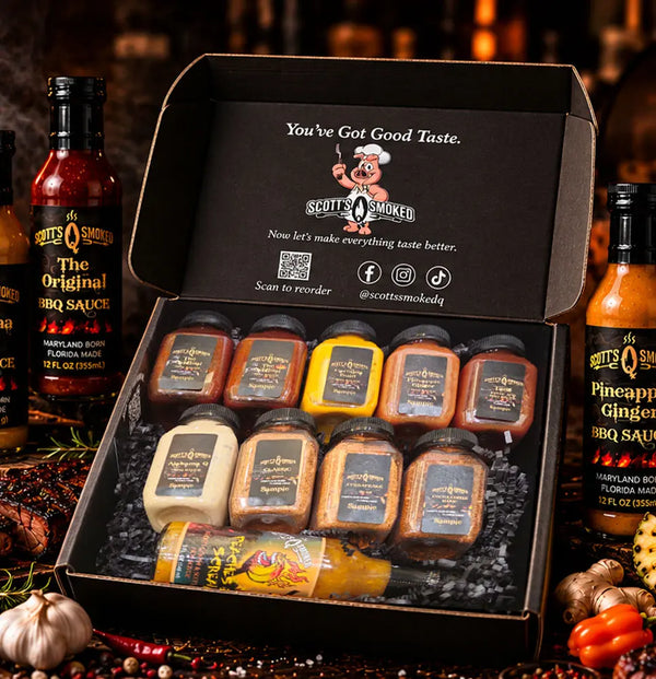 Open Scott’s Smoked Q Sampler Box with 10 sample-size products, surrounded by full-size bottles used as styling props.